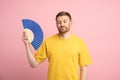 Exhausted man using paper fan suffer from heat. Overheating, stuffiness, hot weather concept Royalty Free Stock Photo