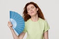 Overheated redhead woman sweating feel uncomfortable waving fan