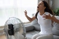 Overheated woman enjoying fresh air, cooling herself by electric fan Royalty Free Stock Photo