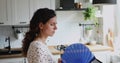 Overheated woman standing in kitchen waving fan cooling herself