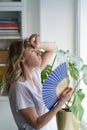 Overheated woman in t-shirt using wave fan suffer from heat sweating, cools herself, feels sluggish