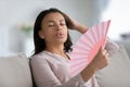 Unhealthy biracial woman breathe fresh air from hand fan