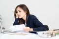 Overhelmed tired young Asian woman sitting at her desk worker wasting time at workplace distracted from boring job, studies Royalty Free Stock Photo