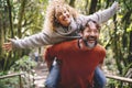 Overjoyed adult couple have fun together at outdoor park in leisure activity. Man carrying woman in piggyback and laugh a lot. Royalty Free Stock Photo