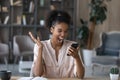 Overjoyed African American woman rejoicing success, holding smartphone, reading news