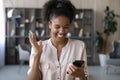 Overjoyed african mixed woman celebrating online success.