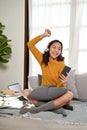 Overjoyed Asian woman listening to music through headphones while relaxing in living room Royalty Free Stock Photo