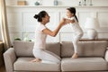 Overjoyed Asian woman with little girl jumping on couch Royalty Free Stock Photo