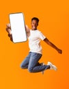 Overjoyed black man jumping and holding smartphone with white screen, mockup for advertisement or app design Royalty Free Stock Photo