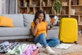 Overjoyed black woman using laptop and talking on phone while booking summer trip and preparing for holidays