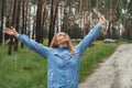 Overjoyed blonde woman in blue raincoat enjoying silence natural green environment woods in the forest. Happy emotion Royalty Free Stock Photo