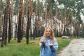 Overjoyed blonde woman in blue raincoat enjoying silence natural green environment woods in the forest. Happy emotion Royalty Free Stock Photo