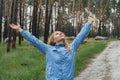 Overjoyed blonde woman in blue raincoat enjoying silence natural green environment woods in the forest. Happy emotion Royalty Free Stock Photo