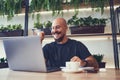 Overjoyed businessman or student uses laptop in cafe shows yes gesture while looks at laptop screen