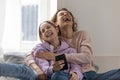 Overjoyed mother and teen daughter laugh using smartphone