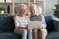 Smiling elderly husband and wife rest on sofa using laptop Royalty Free Stock Photo