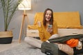 Overjoyed Caucasian young adult woman packing suitcase at home using mobile phone for buying tour or tickets for having journey Royalty Free Stock Photo
