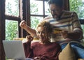 Overjoyed couple exult together in front of laptop sitting at home on the sofa. Excited people man and woman celebrate holding