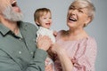 overjoyed couple laughing near beloved granddaughter