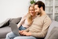 Overjoyed couple in love spending leisure time online with laptop at home. Blonde woman and man looking at the laptop Royalty Free Stock Photo