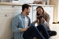 Overjoyed couple sit on floor celebrate anniversary together