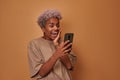 Overjoyed dark skinned woman happy to get money reward on cell phone Royalty Free Stock Photo