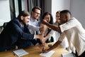 Overjoyed multiethnic businesspeople stack fists engaged in teambuilding