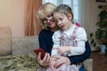 An overjoyed elderly woman and a happy little granddaughter are having fun and watching a funny video on a mobile phone while Royalty Free Stock Photo