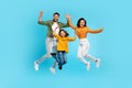 Overjoyed family of three jumping gesturing yes and smiling, parents and daughter posing together in mid air