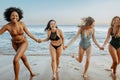 Overjoyed female friends in swimwear having fun and running on the beach, laughing and enjoying their summer vacation Royalty Free Stock Photo