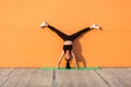 Overjoyed happy girl with perfect athletic body in tight sportswear doing yoga handstand pose with spread legs