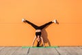 Overjoyed happy girl with perfect athletic body in tight sportswear doing yoga handstand pose with spread legs