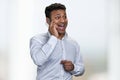 Overjoyed indian businessman talking on transparent phone against blurred background. Royalty Free Stock Photo