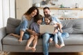 Overjoyed kids watching funny video on computer with parents.