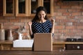 Overjoyed latin female customer open delivery box at kitchen table