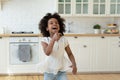 Overjoyed little African American girl holding fork and singing