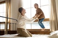 Overjoyed little girl play with loving dad jumping in bedroom