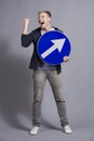 Overjoyed man holding round blue sign with arrow.
