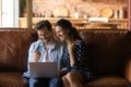 Overjoyed married couple sit on sofa use laptop laugh yes