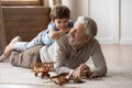 Overjoyed mature grandfather playing with adorable grandson at home
