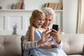 Smiling little girl using smartphone with senior granny Royalty Free Stock Photo