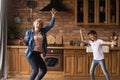 Overjoyed mature woman with little girl dancing in kitchen