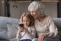 Overjoyed mature woman with little granddaughter using phone together Royalty Free Stock Photo