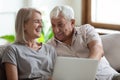 Overjoyed mature woman sitting on sofa with joyful elder man.