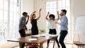 Overjoyed millennial diverse mixed race business people dancing in office.