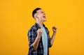 Overjoyed millennial guy making YES gesture with both hands, feeling triumphant over achievement on orange background