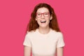 Overjoyed millennial red-haired woman in eyeglasses head shot studio portrait.
