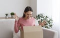 Overjoyed millennial woman opening cardboard box at home