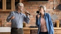 Overjoyed older senior couple having fun sing songs at kitchen