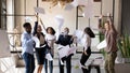 Overjoyed older and young business people throwing papers in air.